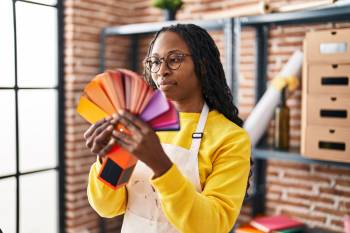 African american woman artist choosing paint color at art studio